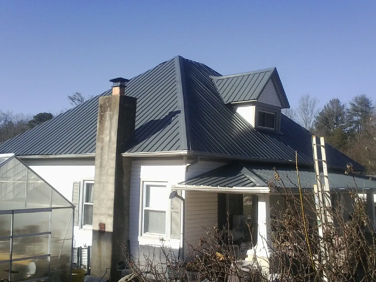 Dark blue standing seam metal roof on a white farmhouse with dormer — Slate & Tile Roof Repair by Roofing Brothers in Mountain Home