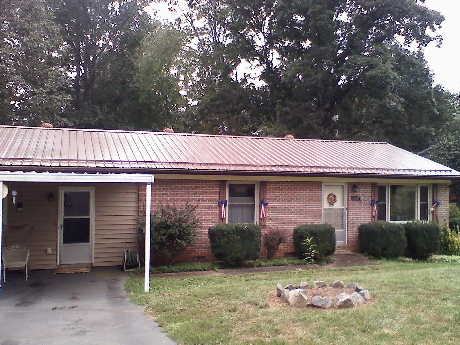Bronze metal roof and carport on a brick ranch home — Roof Repair work by our crew in Mountain Home