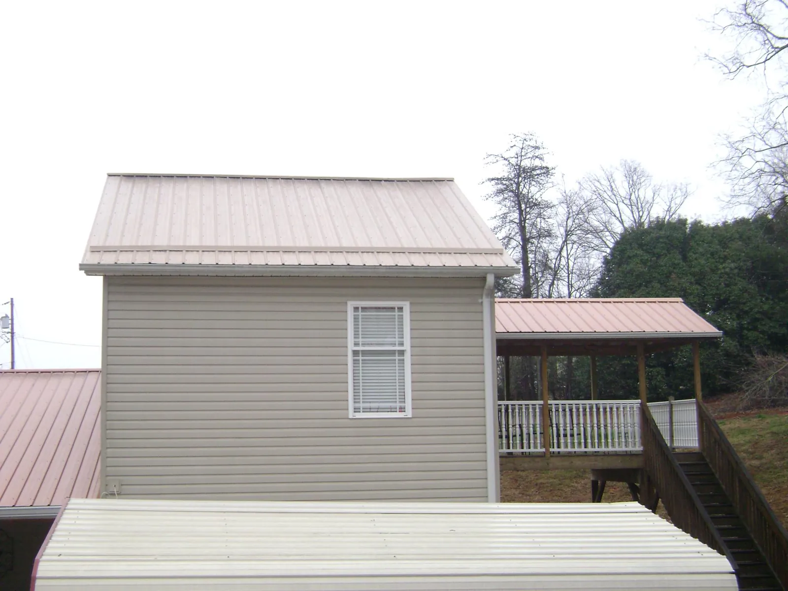 Tan metal roofs on a two story addition and attached porch, from a Roof Replacement job in Mountain Home
