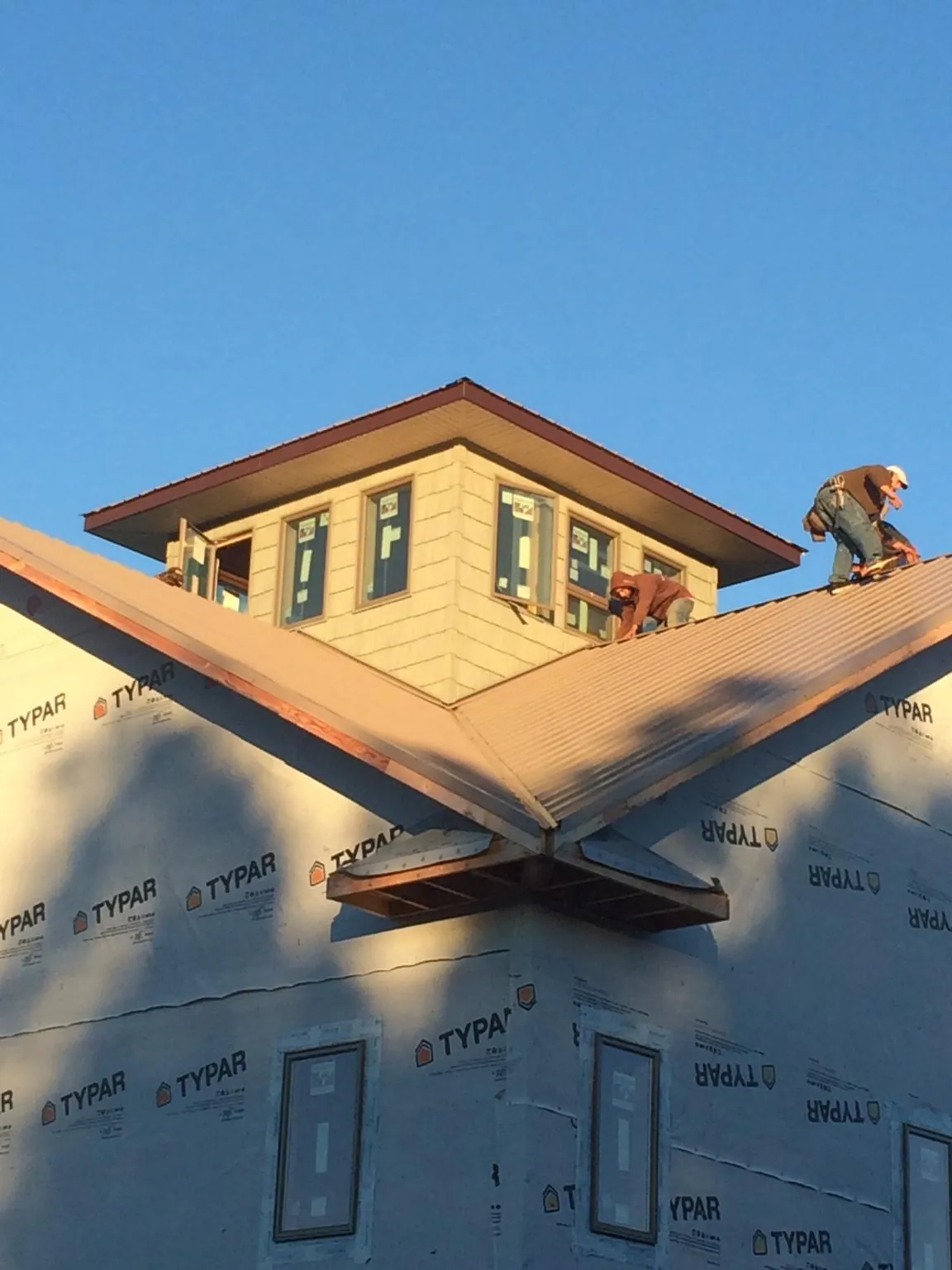 Roofers working around a rooftop cupola on a new metal roof at sunset — Roof Waterproofing in Mountain Home by Roofing Brothers